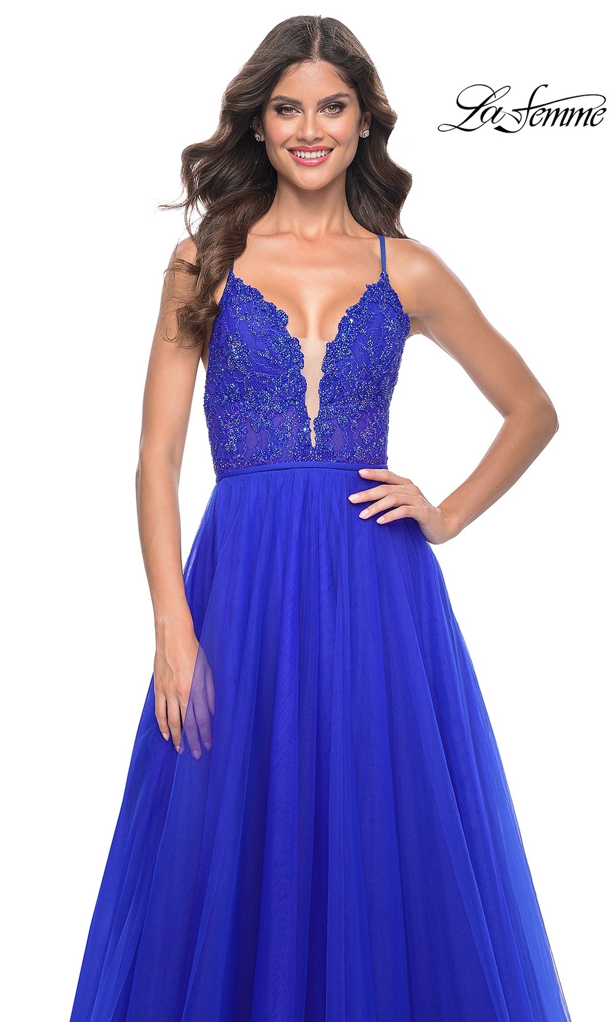 A woman models the La Femme Deep V-Neck Long Tulle Prom Gown 32059 in royal blue, featuring an A-line silhouette, lace bodice, deep V-neck, and long tulle skirt against a white background.